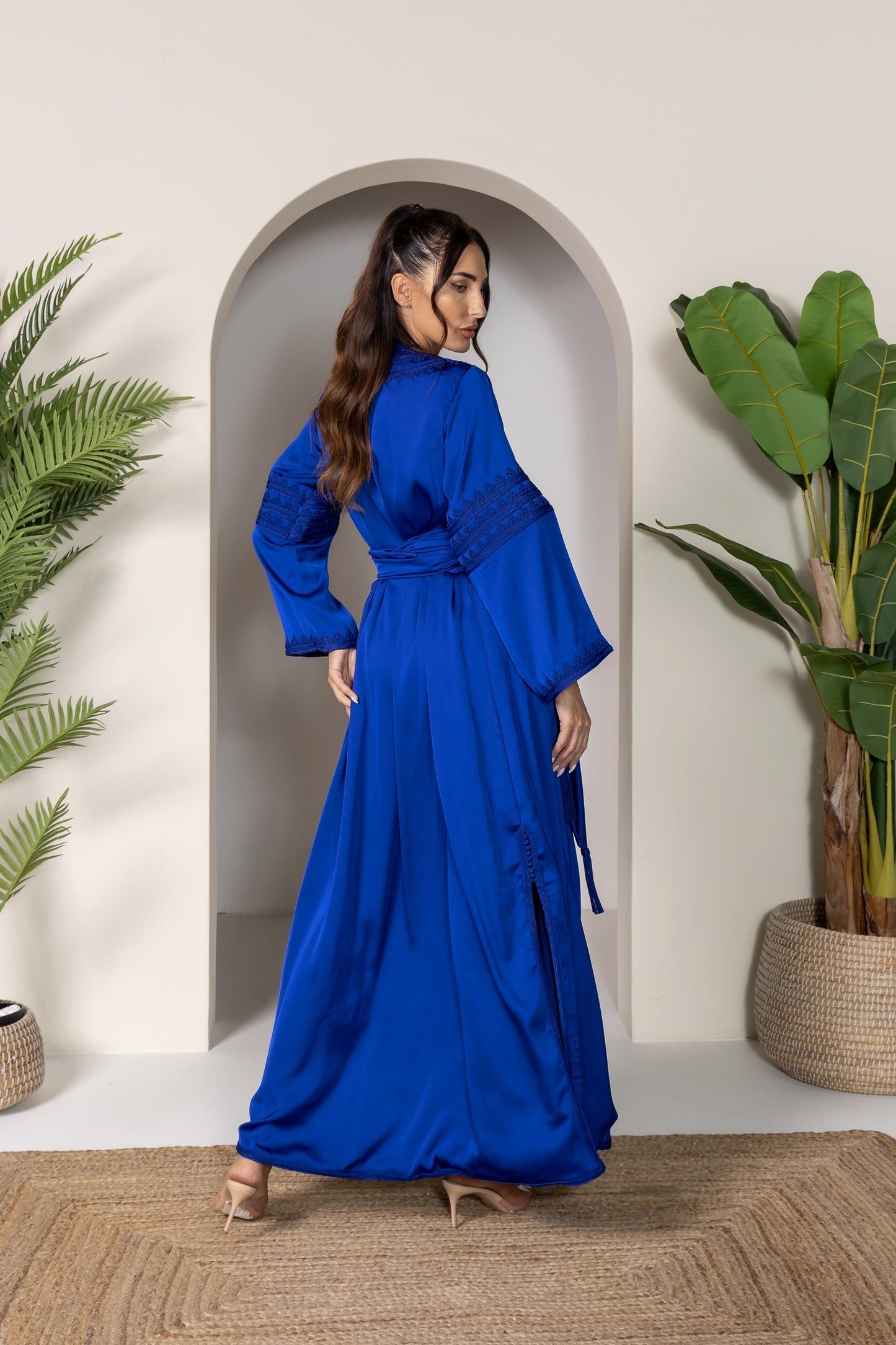 Back view of a blue Moroccan kaftan with flowy fabric and side slit