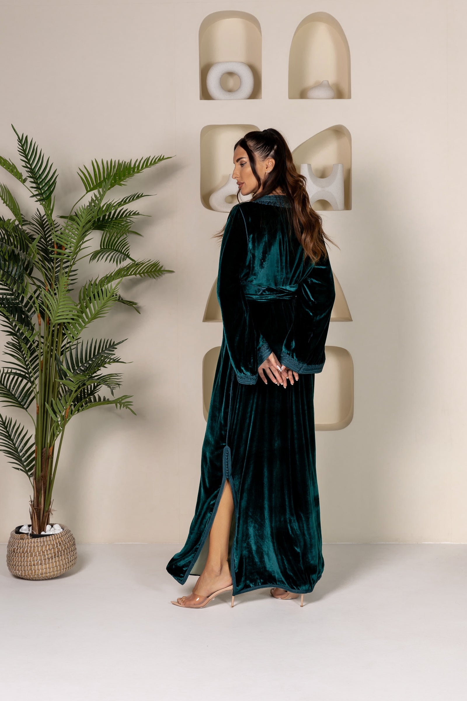 Back view of a green velvet Moroccan kaftan with flowy fabric and slit