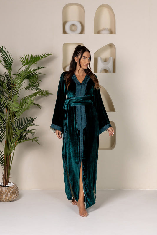 Woman in green velvet Moroccan kaftan with wide sleeves and a tied belt